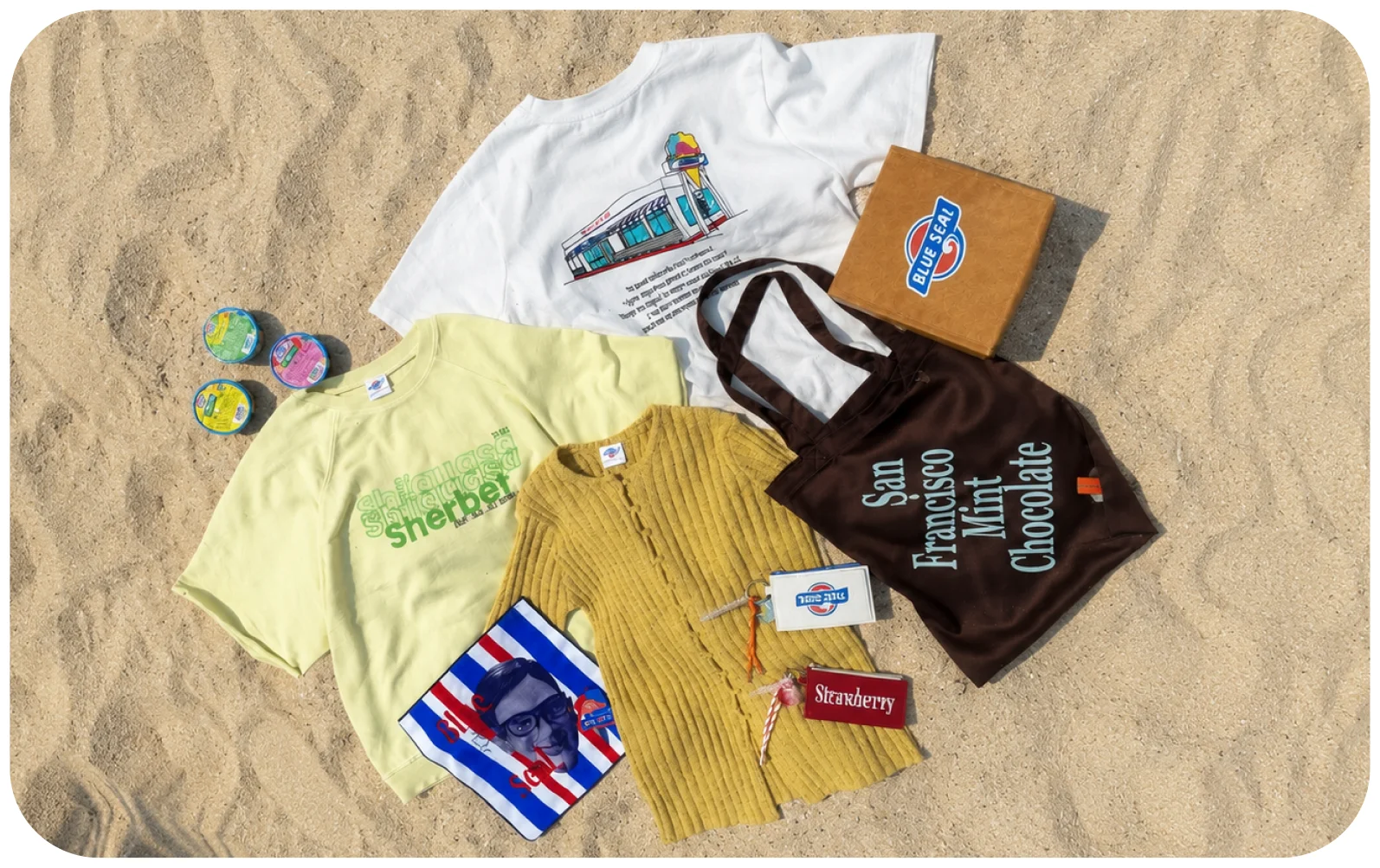 ビーチの砂浜にBLUE SEAL×AMERICAN HOLICのコラボアイテムを並べた写真